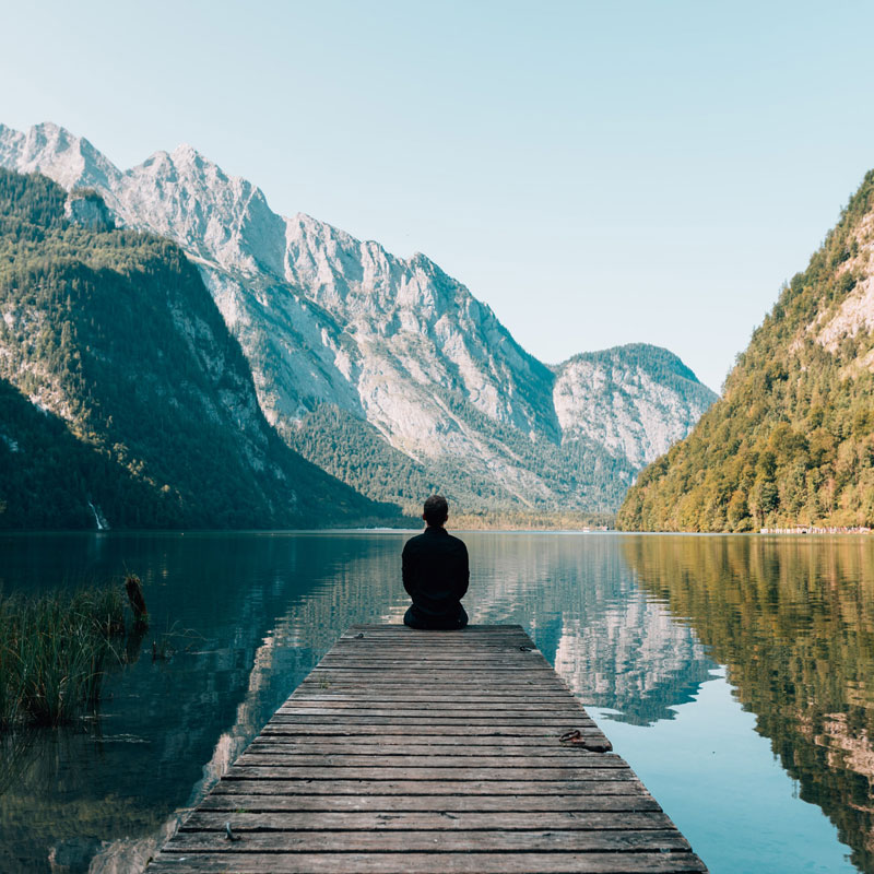 Man sitting on dock looking at mountain lake on one of his annual multi trips Title: Man on Dock on Mountain Lake