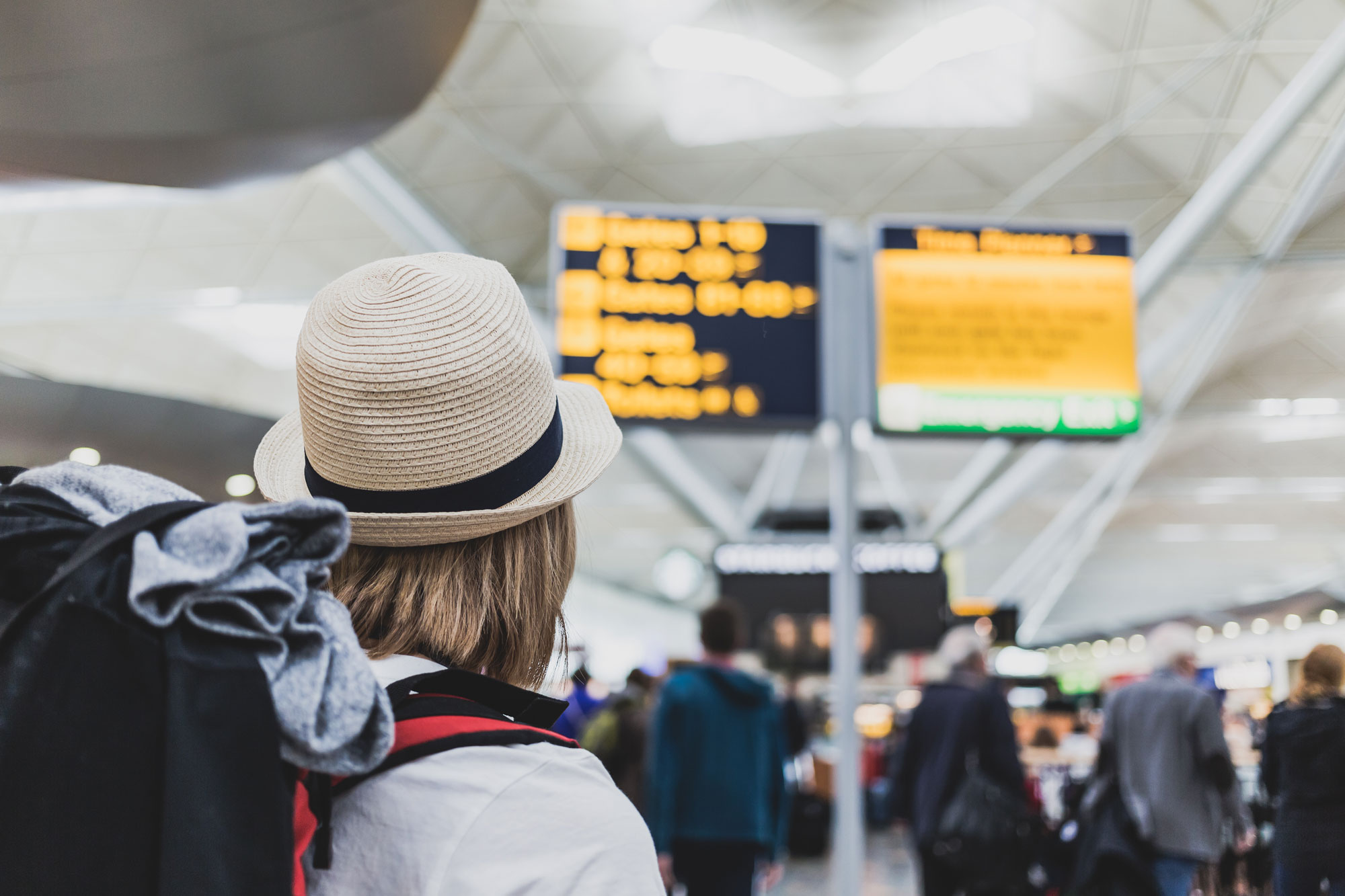 A woman using backpacker travel insurance at the airport checking flights.